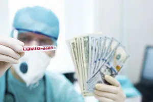 Healthcare worker showing COVID-2019 test tube and fan of cash