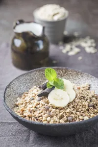 Healthy breakfast bowl. Granola with chocolate and banana on white wooden table