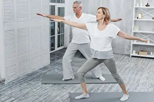 Healthy couple performing exercising yoga mat home