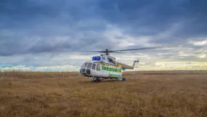 Helicopter taking off in a field against a beautiful sky
