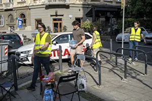 Helpers with high-visibility waistcoats receive a donation of water at a protest in Belgrade