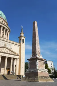 High obelisk next to an architectural masterpiece with dome