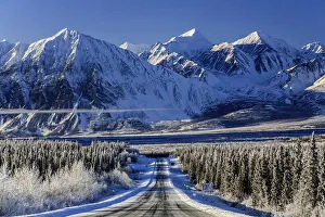 Highway in winter landscape in front of snow-covered mountains