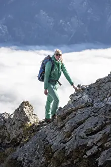 Hiker at Ettaler Manndl, view over mountain landscape and sea of clouds