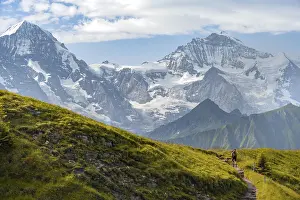 Hiker on hiking trail, snow-covered mountain peaks