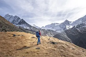Hiker on hiking trail, snow-covered mountains