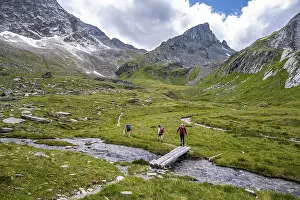Hiker on hiking trail, stream with bridge