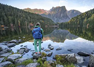 Hiker at the lake, mountain peaks of the Oetztal Alps are reflected in Lake Piburger See