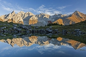 Hiker reflected in mountain lake in front of mountains