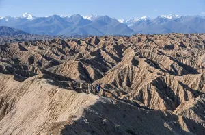 Hiker walking along a canyon, Tian Shan mountains in the background