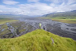 Hiker, young man on a hill, view over alluvial land