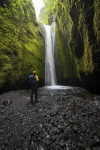 Hikers in front of waterfall, river in Nauthusagil Gorge