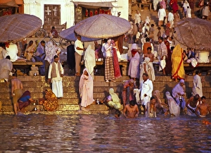 Hindus, die im heiligen Fluss Ganges in Varanasi, Indien, baden, darunter ein weisser Europaeer, der sich entkleidet 1974