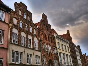 Historic brick architecture with rows of windows under a dramatically cloudy sky in an old town