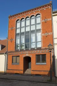 Historic building with brick facade and large windows under a clear sky