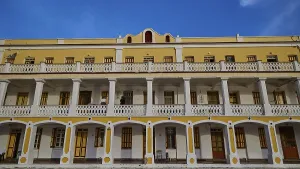 Historic building with yellow facade and balconies against a blue sky