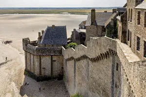 Historic castle wall with a view of a wide expanse of sand and distant buildings under a clear sky