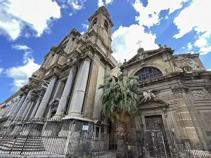 Historic church with large columns and a palm tree in the foreground under a blue sky