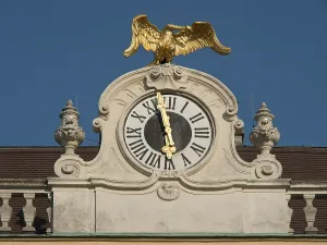 Historic clock with gilded eagle on a building against a clear sky