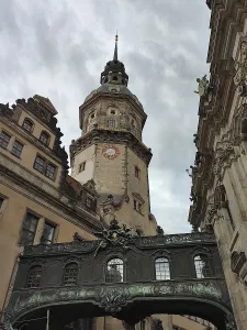 Historic clock tower, Hausmannsturm with a view of the residential palace's cabinet bridge against a cloudy sky