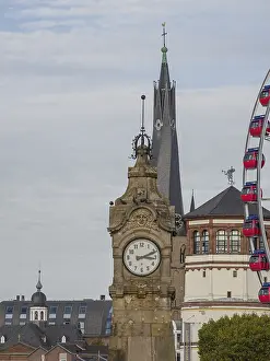 Historic clock tower in front of modern architecture and a Ferris wheel