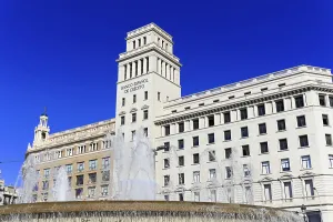 A historic fountain in front of a majestic building under a clear blue sky