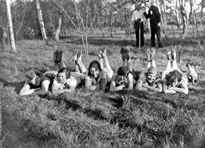 Historic photograph, women lying in the grass with their feet in the air