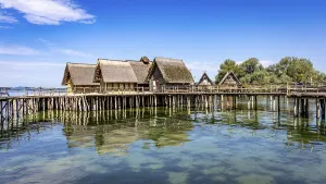 Historic pile dwellings on the shore of a lake with reflecting water