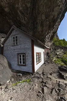 Historical wooden houses sheltered under a massive rock overhang
