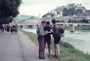 Two hitchhikers being helped with directions by a man, Salzach River riverbank, Salzburg, Austria early 1960s