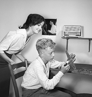 Hobby in the 1950s. A boy is sitting at a table with a plastic model of an American bomb aircraft B-26