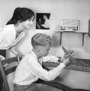 Hobby in the 1950s. A boy is sitting at a table with a plastic model of an American bomb aircraft B-26