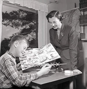 Hobby in the 1950s. A boy is sitting at a table with a plastic model of an American bomb aircraft B29