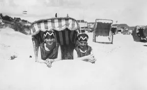 Holiday, two women lying on the beach in front of a beach chair
