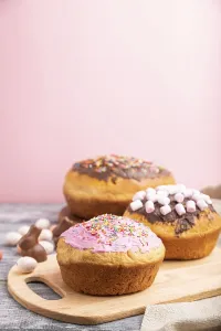 Homemade glazed and decorated easter pies with chocolate eggs and rabbits on a gray and pink background