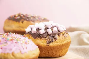 Homemade glazed and decorated easter pies with chocolate eggs and rabbits on a gray and pink background