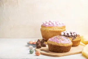 Homemade glazed and decorated easter pies with chocolate eggs and rabbits on a white concrete background