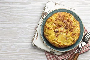 Homemade Spanish tortilla - omelette with potatoes on plate on white wooden rustic background top view