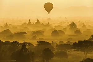 Hot air balloon over the landscape in the early morning fog
