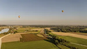 Two hot air balloons float calmly over the wide fields and the Danube (Lower Bavaria)