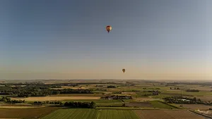 Two hot-air balloons float majestically over the rolling hills