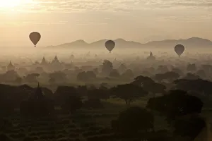 Hot air balloons over landscape with stupas