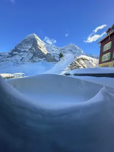 Hotel and Snowcapped Mountain Peak Eiger North Face at 3970 Meter High in a Sunny Winter Day with Blue Sky