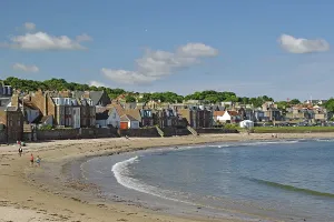 Houses along a beach with walkers by the sea under a blue sky on a sunny day