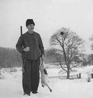 Hunter in the 1940s. A man is standing and holding a hare he has shot when hunting for the traditional christmas hare