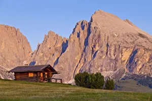 Hut on the Seiser Alm alpine meadow with a view towards Sasso Lungo and Sasso Piatto mountains