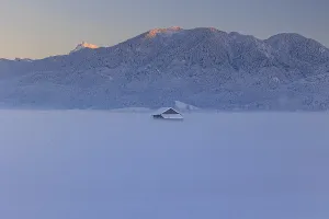Hut in the snow in front of mountains