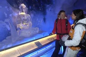 Ice Buddha statue admired by tourists in the ice cave in the Gletscherpalast or Glacier Palace