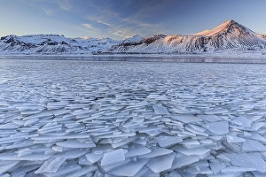 Ice floes on a lake in front of snowy mountains