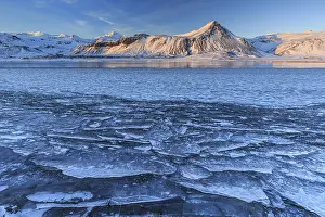 Ice floes on a lake in front of snowy mountains